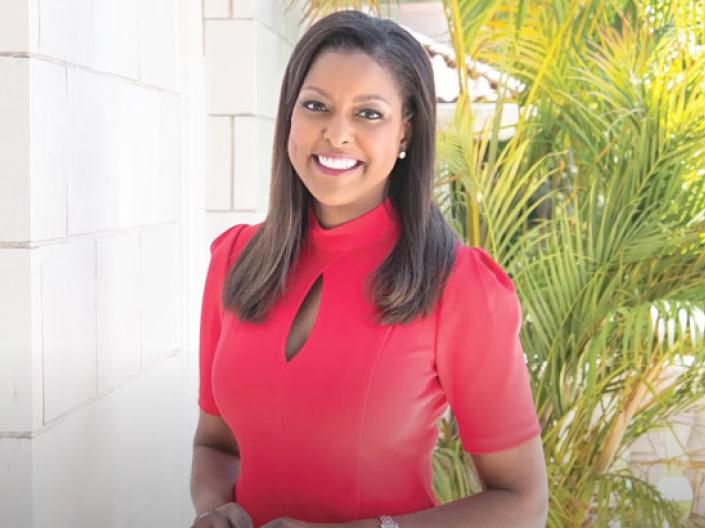 Lori Stokes smiles in front of some plants